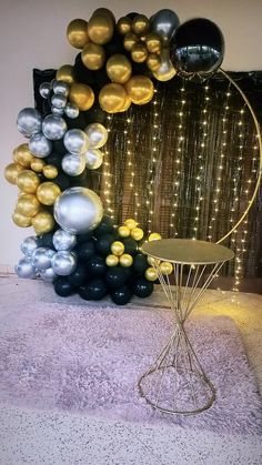 a bunch of balloons that are sitting on the ground next to a table and chair