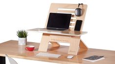 a wooden desk with a laptop and mouse on it, along with a potted plant