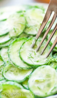 cucumber slices are being cut with tongs in a white bowl on a table