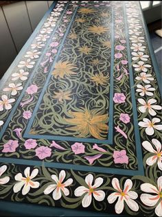 the table is decorated with flowers and vines on it's sides, along with an intricately designed border