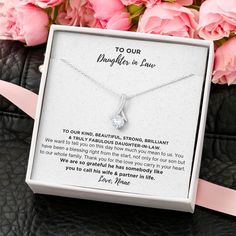 a necklace in a gift box with pink roses behind it and a message to our daughter in law