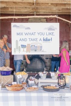 people are standing around a table with food and drinks in front of a sign that says mix what you like and take a hike