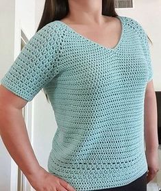 a woman standing with her hands on her hips wearing a blue crochet top