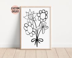 a black and white drawing of flowers in a wooden frame on the floor next to a wall