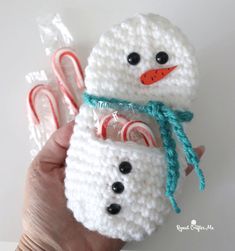 two crocheted snowmen are holding candy canes