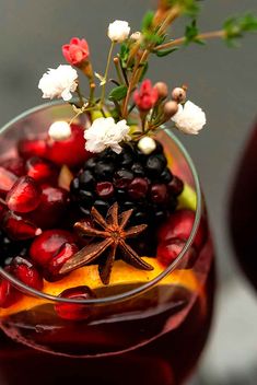 a glass filled with fruit and flowers on top of a table