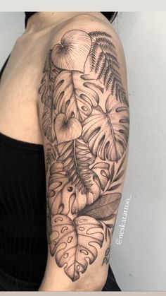 a black and white photo of a woman's arm with flowers, leaves and butterflies on it