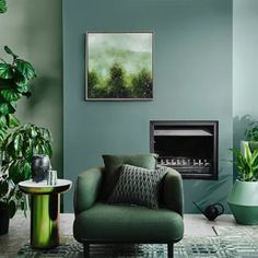 a living room with green walls and plants in the corner, along with a fireplace