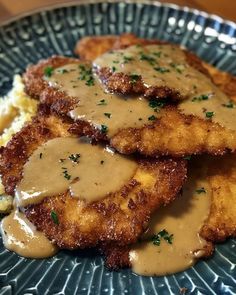 some fried chicken with gravy on top of mashed potatoes and gravy