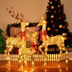 two lighted reindeers in front of a christmas tree