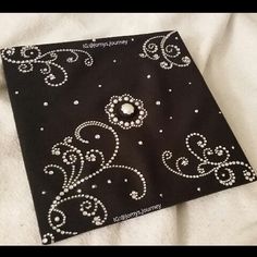 an embroidered black and white cloth with silver beading on the edges is laying on a bed