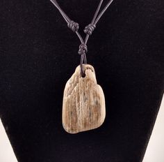 a necklace with a wooden pendant on a mannequin's dummy head and leather cord