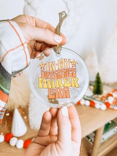 a person holding up a glass ornament with the words, i am my distance maker girl on it