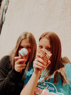 two girls eating ice cream cones in front of a building