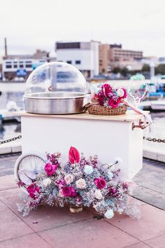 an ice cream cart with flowers on the side and a basket full of bubbles above it