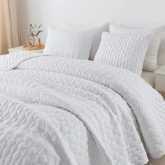 a bed with white comforter and pillows on it