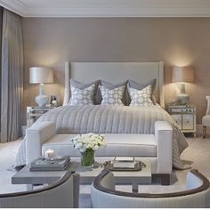 a large white bed sitting in a bedroom next to two tables with lamps on them