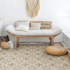 a white couch sitting on top of a rug next to a wooden bench with pillows