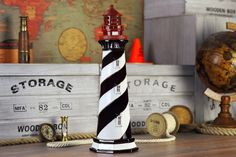 a black and white lighthouse sitting on top of a wooden table next to a globe