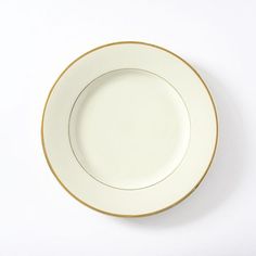 an empty white plate with gold trim against a white background