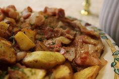 a plate full of potatoes and meat with herbs on top, sitting on a table