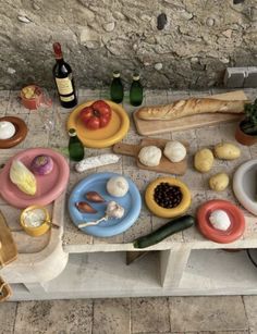 a table topped with plates and bowls filled with food next to wine bottles on top of a stone floor