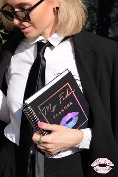 a woman in a suit and tie holding a book with lipstick on it's cover