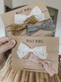 three small bows are being held up in front of a card with the words billy bibs written on it