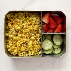 a metal container filled with assorted vegetables and fruit next to cucumber slices