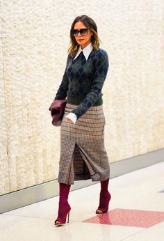 a woman is wearing a skirt and sweater while standing in front of a white wall