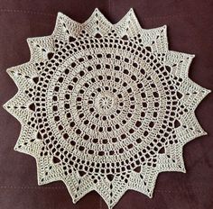 a crocheted doily is shown on a brown surface