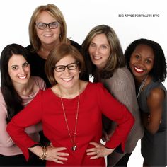 a group of women standing next to each other in front of a white background with one woman smiling at the camera