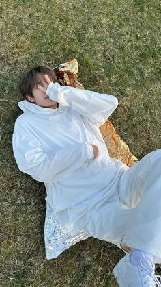 a person laying on the ground with their head in his hands and wearing a white outfit