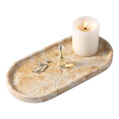 a marble tray with a lit candle and two silver rings on it