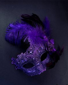 The brocade lace design with feathers add a touch of sophistication and the jewels are carefully placed to catch the light and enhance your beauty. Securely and comfortably fits every face shape so you can enjoy a perfect evening at the masquerade ball.

Age Group/Gender - Adult/Women

Size/Type - One size fits all adults

Mask Color - Purple

Mask Material - Polyresin/Fabric

Accent Material - Gems Black And Purple Masquerade Mask, Masquerade Outfit Ideas Purple, Purple Masquerade Quinceanera Ideas, Dark Purple Masquerade Mask, Elegant Headpieces For Carnival Masquerade, Elegant Headpieces For Masquerade Carnival, Feathered Masquerade Mask For Carnival Party, Masquerade Carnival Headpiece, Elegant Formal Masks For Carnival