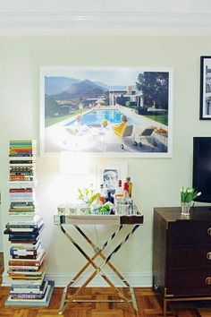 a living room filled with lots of furniture and books on top of a wooden table