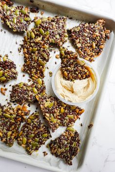 a tray filled with crackers covered in nuts and hummus