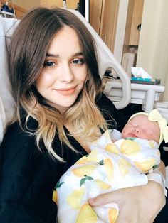 a woman is holding a baby in her arms and smiling at the camera while sitting in a hospital bed