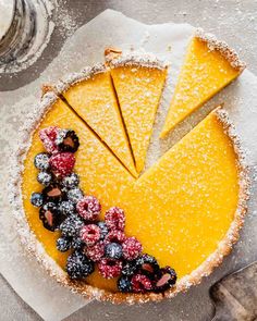 a lemon tart with berries and powdered sugar on top, ready to be eaten