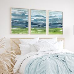 two paintings on the wall above a bed in a room with white sheets and pillows