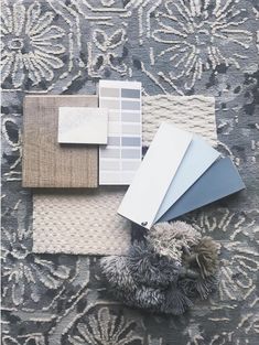 the carpet is covered with different shades of gray and white paint swatches, rugs, and other items