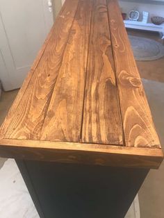 a wooden table top sitting on top of a black metal stand in front of a white door