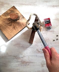 a person holding a pair of scissors near some wood planks and other crafting supplies