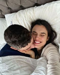 a man and woman laying in bed with their heads close to each other as they cuddle