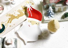 a santa clause figurine sitting on top of a table next to other christmas decorations