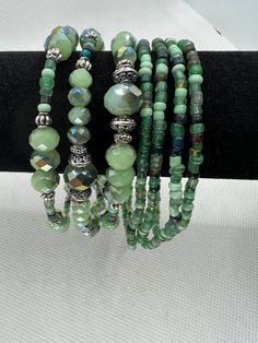 the bracelets are made with green glass beads and silver metal clasps on black leather