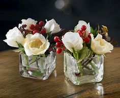 two clear vases with white flowers and red berries