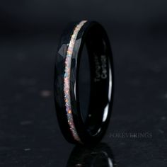 a black wedding band with white and pink opal inlays on the inside