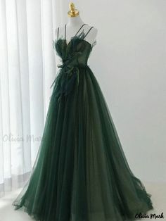 a green dress is displayed on a mannequin headdress in front of white curtains