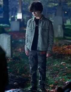 a young man standing in the middle of a cemetery